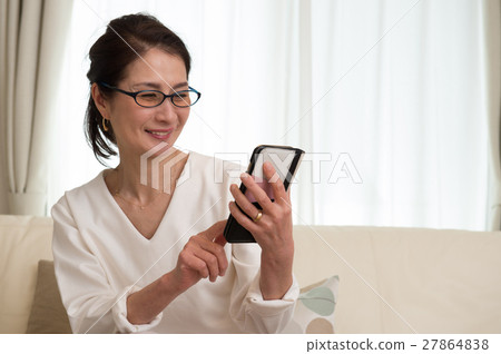 觀看有放大鏡的一名中年日本婦女一個智能手機 27864838