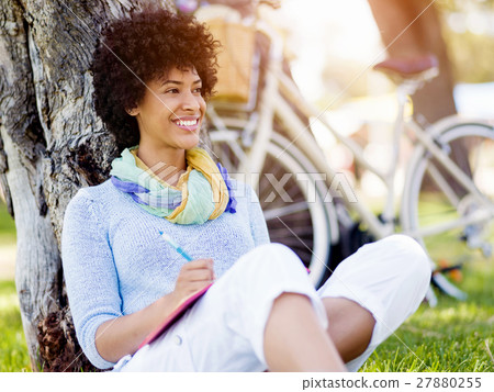 Beautiful young woman writing in her diary outdoors Beautiful young woman writing in her diary outdoors 27880255