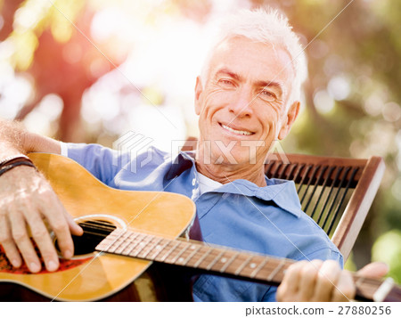 Senior man plying guitar outdoors Senior man plying guitar outdoors 27880256