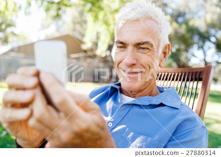 LoMature man outdoors using mobile phone 27880314