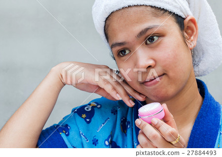 Woman applying moisturizer cream on her pretty face 27884493