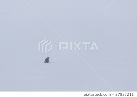 lonely fisherman sitting on the frozen river 27885211