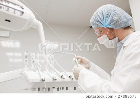 Dentist leaned over patient in 's chair at clinic 27885575