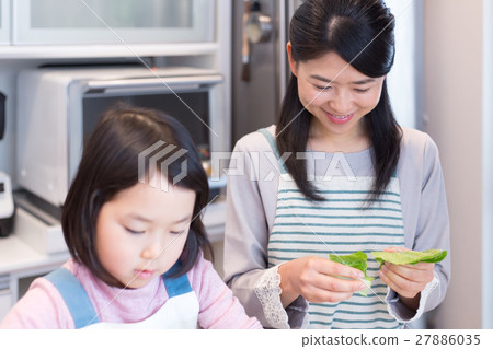 A girl who helps with a mother who cooks in the kitchen 27886035