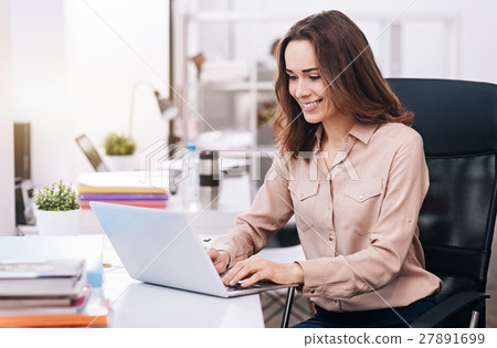 Smiling young businesswoman typing in the office Smiling young businesswoman typing in the office 27891699