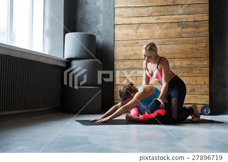 Woman with yoga instructor in class, asana cobbler Woman with yoga instructor in class, asana cobbler 27896719