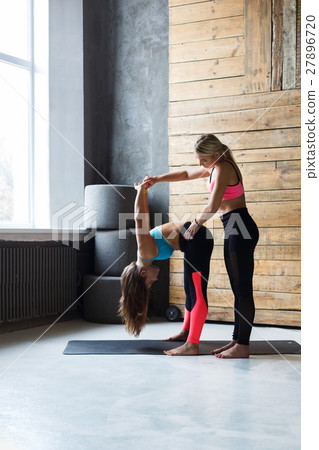 Woman with yoga instructor in class, forward bend 27896720