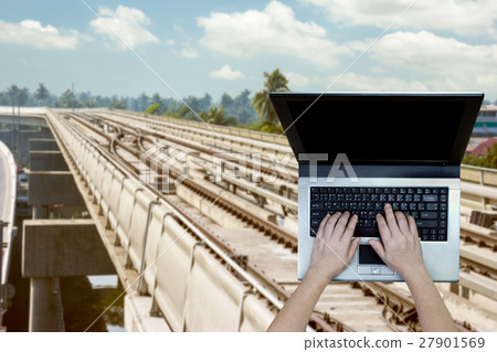 Woman using laptop with blurry metro background Woman using laptop with blurry metro background 27901569