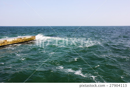 Old concrete, stone pier into the sea. Old concrete, stone pier into the sea. 27904113
