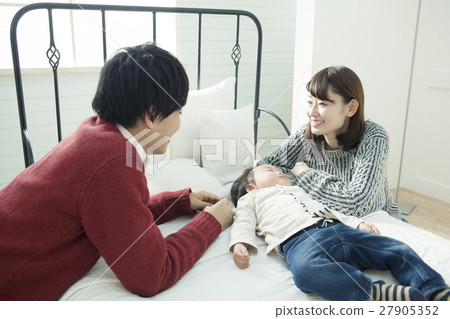 A couple looking at a child's sleeping face 27905352