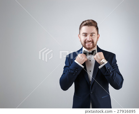 Handsome man in tuxedo and bow tie looking at 27916895