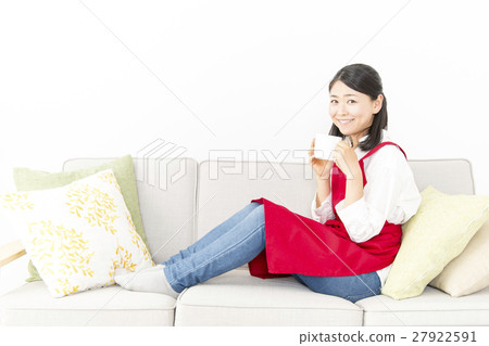 A woman sitting on the sofa and drinking coffee at the camera's eyes 27922591