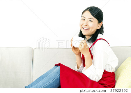 一個女人坐在沙發上,在相機的眼睛喝咖啡 一個女人坐在沙發上,在相機的眼睛喝咖啡 27922592