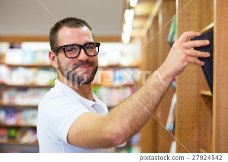 Man picking a book in a library 27924542