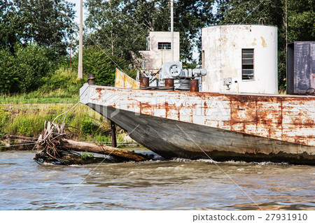 Old rusty anchored boat by riverside 27931910