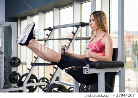 Young fit woman at the gym doing abs workout Young fit woman at the gym doing abs workout 27944207