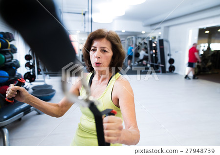 Senior woman in gym working out with weights. Senior woman in gym working out with weights. 27948739