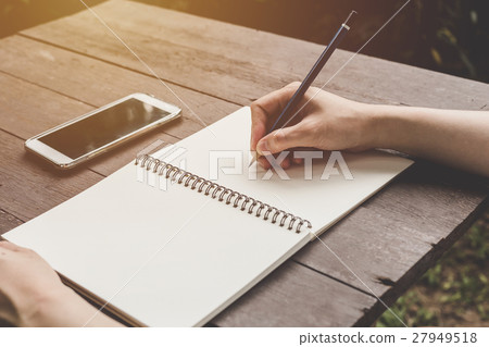 close up hand woman writing notebook on wood table 27949518