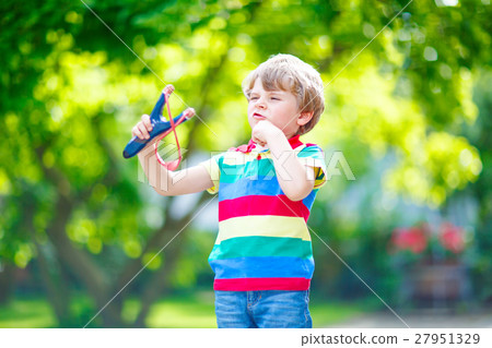 little kid boy shooting wooden slingshot little kid boy shooting wooden slingshot 27951329