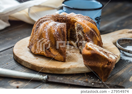Marble cake cup of coffee and powder sugar . 27954974