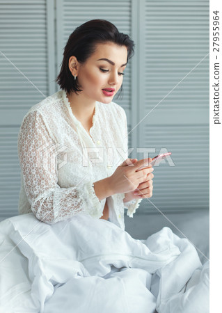 Woman in the bed reading messages. 27955964