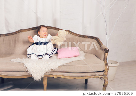 happy little baby girl sitting on the couch with 27956169