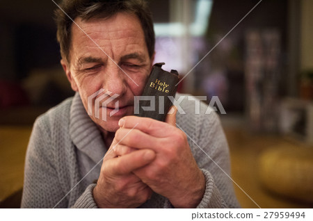 Senior man praying, holding Bible in his hands Senior man praying, holding Bible in his hands 27959494