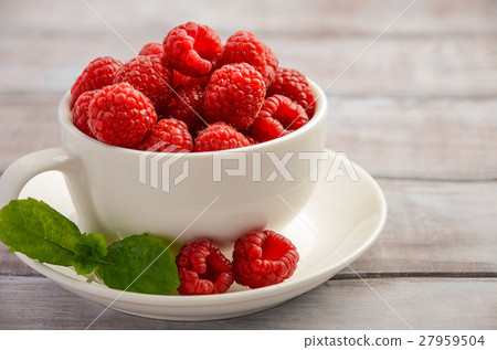 Ripe sweet raspberries in white cup  27959504