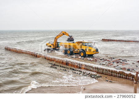 excavator loads a truck stones on the beach 27960052