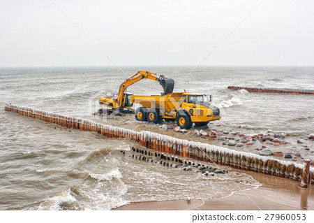 excavator loads a truck stones on the beach 27960053