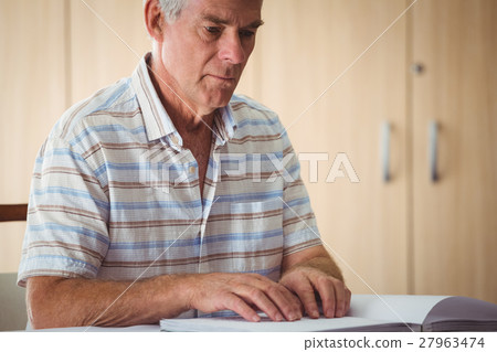 Senior man using braille to read Senior man using braille to read 27963474