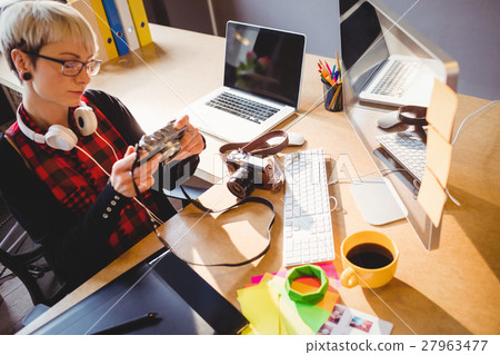Graphic designer looking at pictures in digital camera Graphic designer looking at pictures in digital camera 27963477