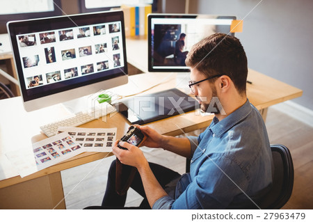 Graphic designer looking at pictures in digital camera Graphic designer looking at pictures in digital camera 27963479