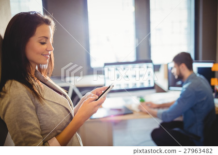 Smiling graphic designer using mobile phone Smiling graphic designer using mobile phone 27963482
