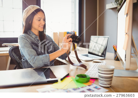 Graphic designer looking at pictures in digital camera 27963603
