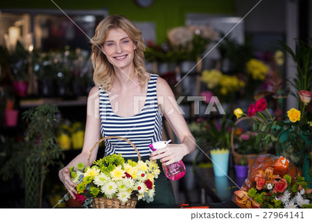 Female florists spraying water on flowers in flower shop 27964141