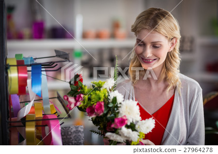 Female florist preparing a flower bouquet Female florist preparing a flower bouquet 27964278