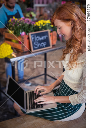 Female florist sitting and using laptop Female florist sitting and using laptop 27964279