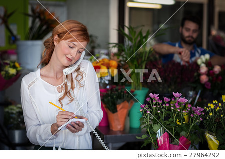 Female florist taking an order on telephone Female florist taking an order on telephone 27964292