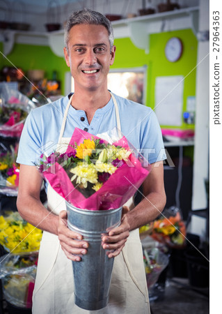 Male florist holding flower bouquet at flower shop Male florist holding flower bouquet at flower shop 27964363