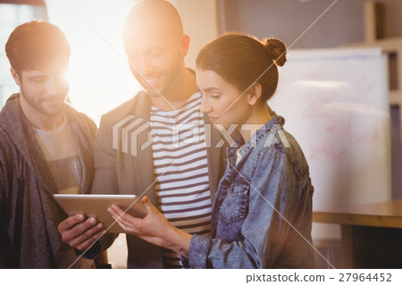 Graphic designer using digital tablet with his coworker Graphic designer using digital tablet with his coworker 27964452
