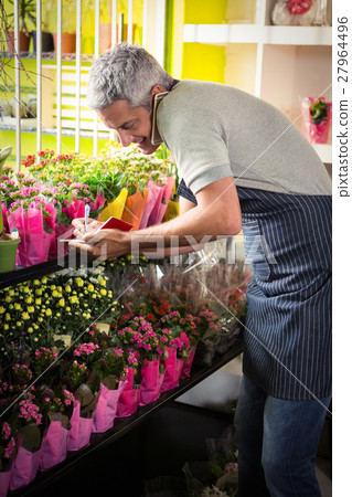 Male florist taking order on mobile phone Male florist taking order on mobile phone 27964496