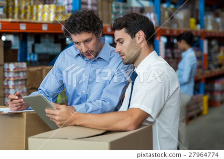 Portrait of managers are working with a tablet in the middle of cardboard boxes 27964774