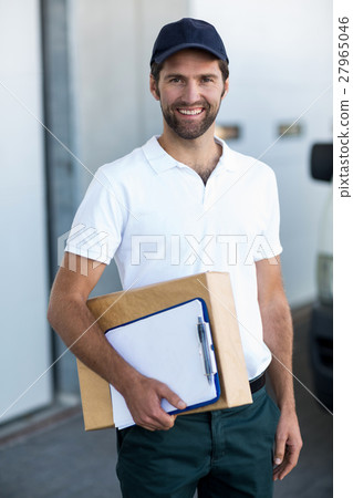 Portrait of delivery man is holding cardboard box and posing Portrait of delivery man is holding cardboard box and posing 27965046