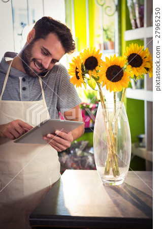 Male florist talking on mobile phone while using digital tablet Male florist talking on mobile phone while using digital tablet 27965250