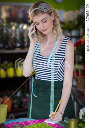 Female florist taking order on mobile phone 27965409