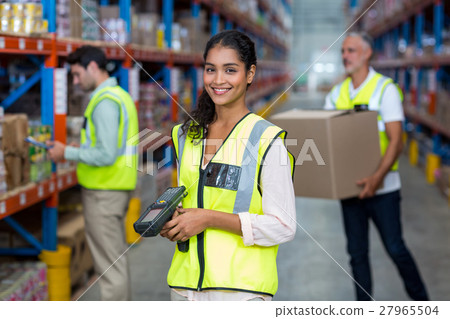 Happy worker posing and smiling to the camera in front of her colleagues Happy worker posing and smiling to the camera in front of her colleagues 27965504
