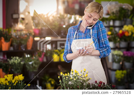 Female florist taking an order on mobile phone Female florist taking an order on mobile phone 27965528