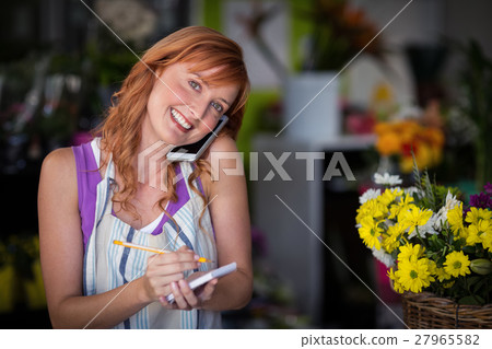 Female florist taking an order on mobile phone Female florist taking an order on mobile phone 27965582