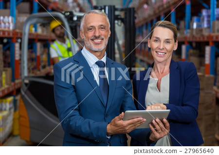 Portrait of happy managers holding a tablet and looking the camera Portrait of happy managers holding a tablet and looking the camera 27965640